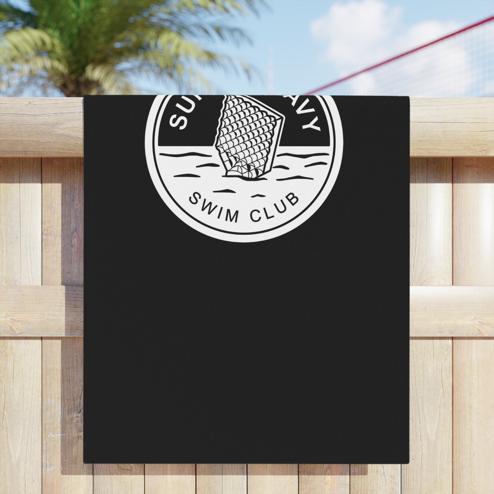 SpaceX Super Heavy booster-inspired beach towel, playful swim club design, hanging on a fence. 